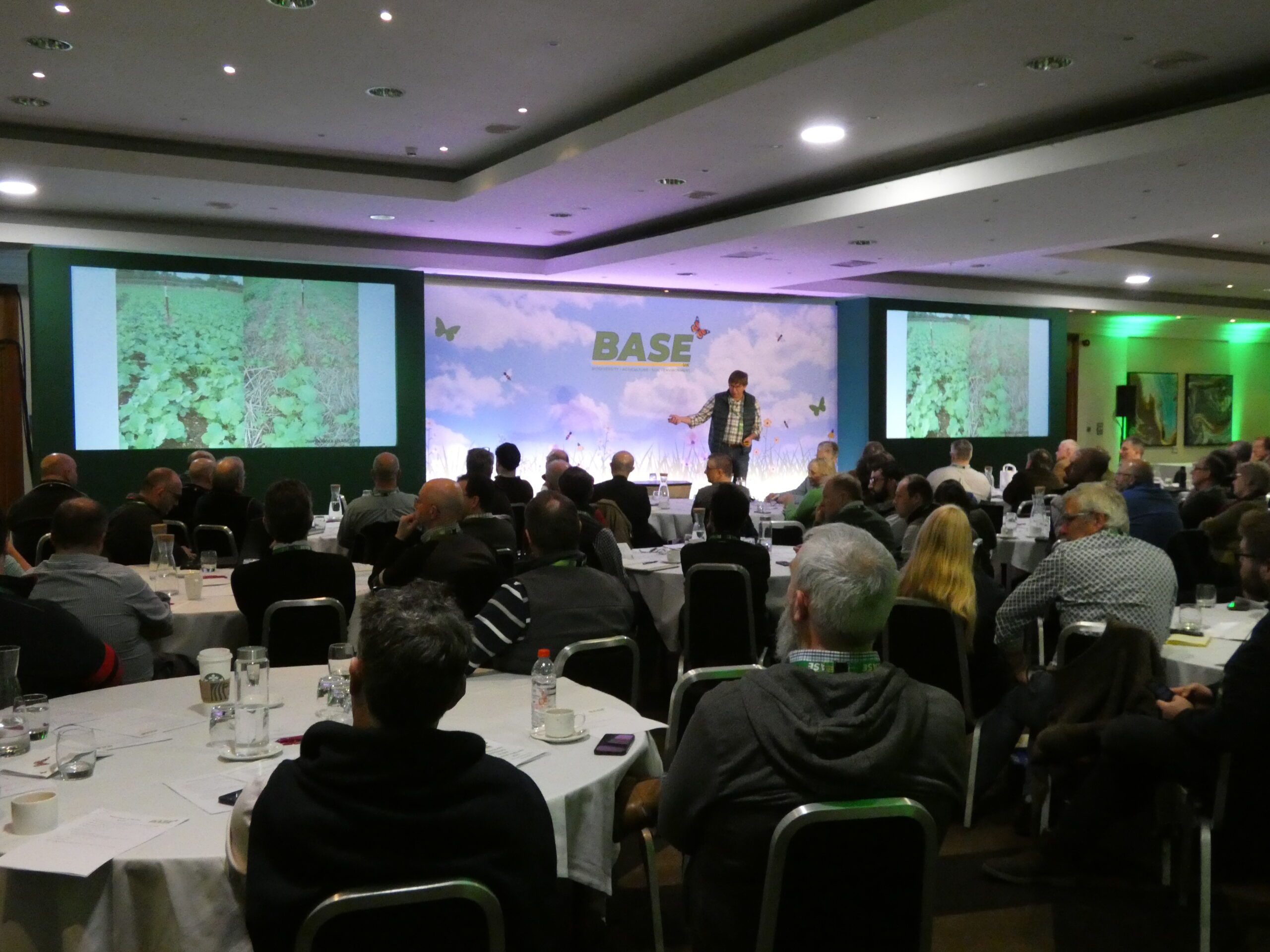 Stage, speaker and audience members at tables for BASE event at Crowne Plaza Nottingham