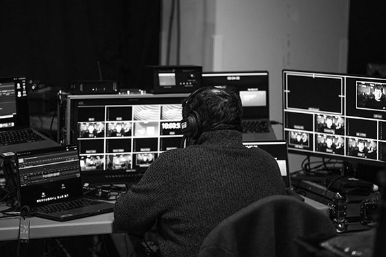 Black and white photo of technical production crew working on screens behind the scenes at an e.on event